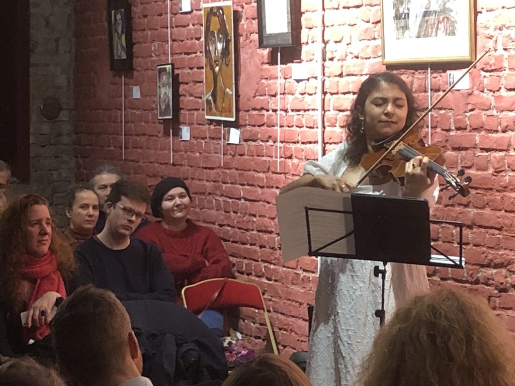 Photographie de la prestation live de la violoniste Astrid Rios devant les tableaux expressionnistes de Jérôme Selosse à Cambre Expo.